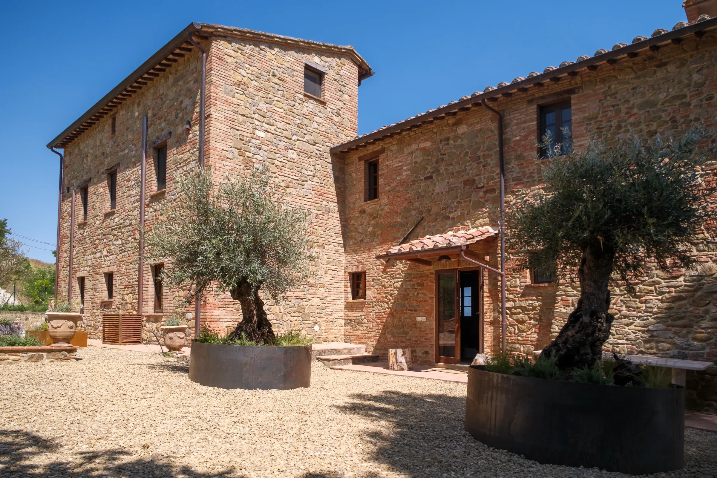 Façade en pierre et oliviers dans la cour de la villa