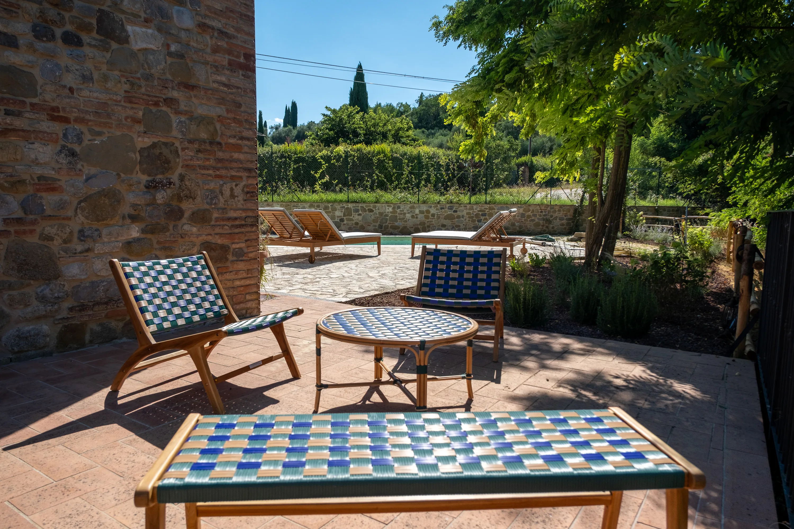 Salon de jardin tressé à l’ombre de l’arbre, près de la piscine