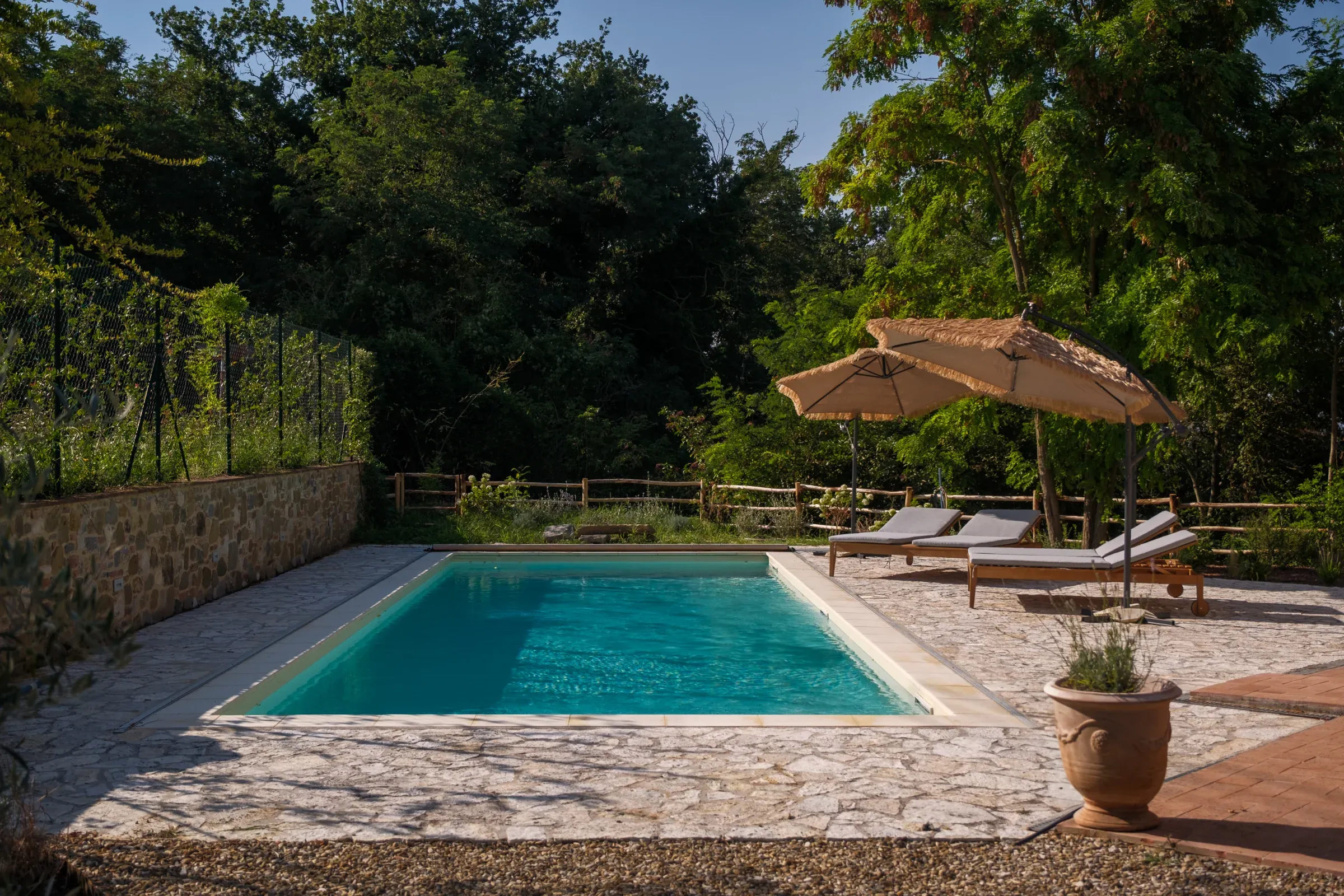 Piscine entourée de pierre et de transats