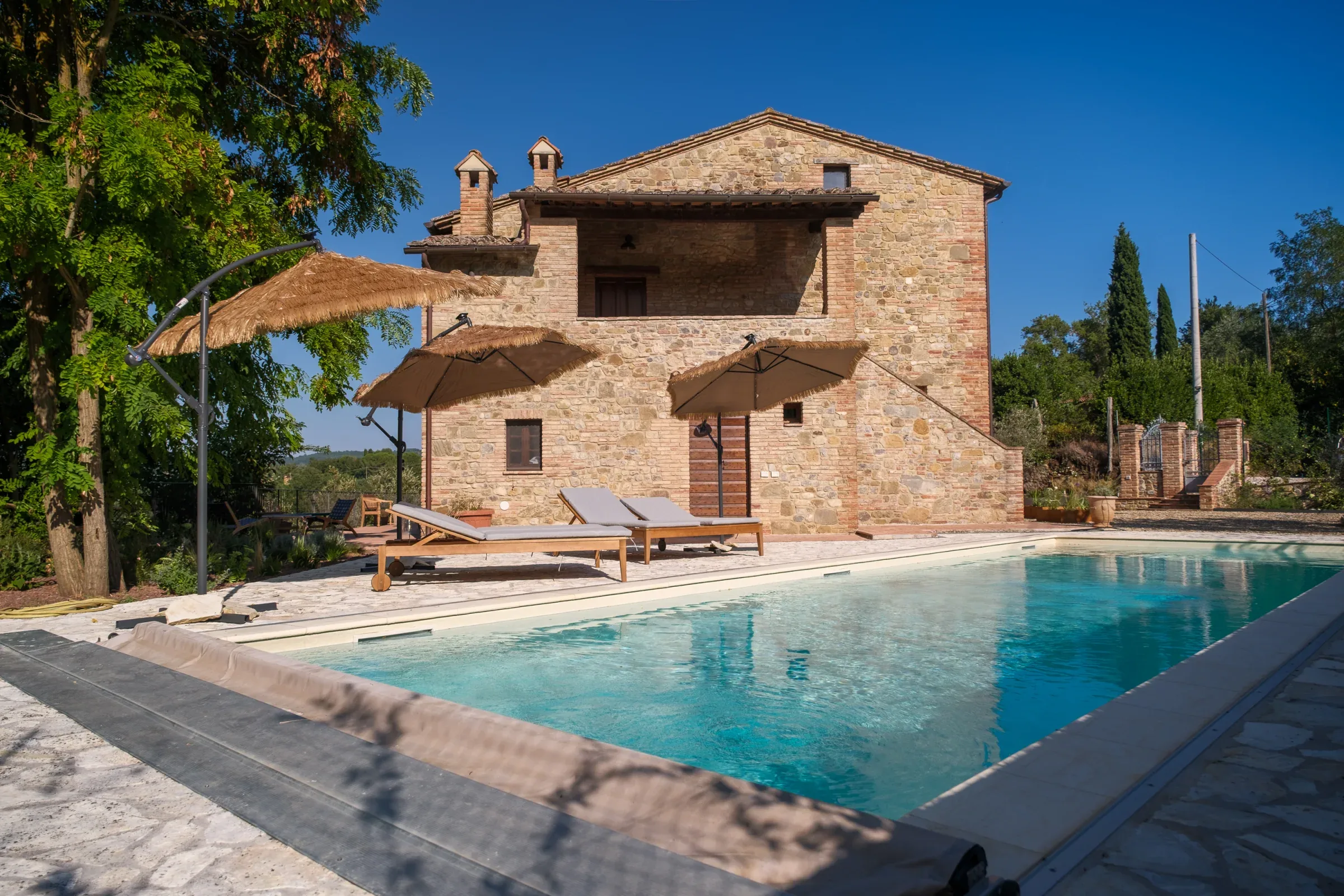 Piscine et façade en pierre sous les parasols