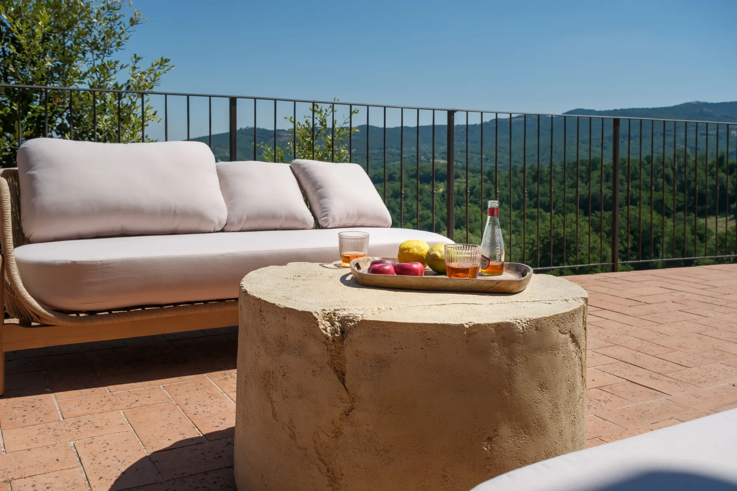 Sofa im Freien und Tisch mit Obst vor dem Tal