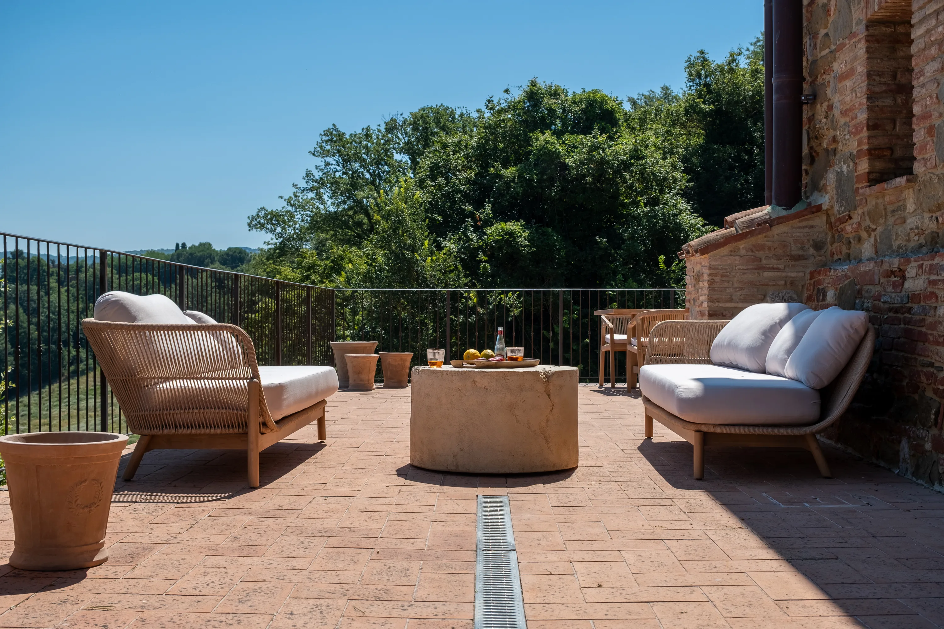 Divani in rattan e tavolo in pietra sulla terrazza, di fronte alle colline